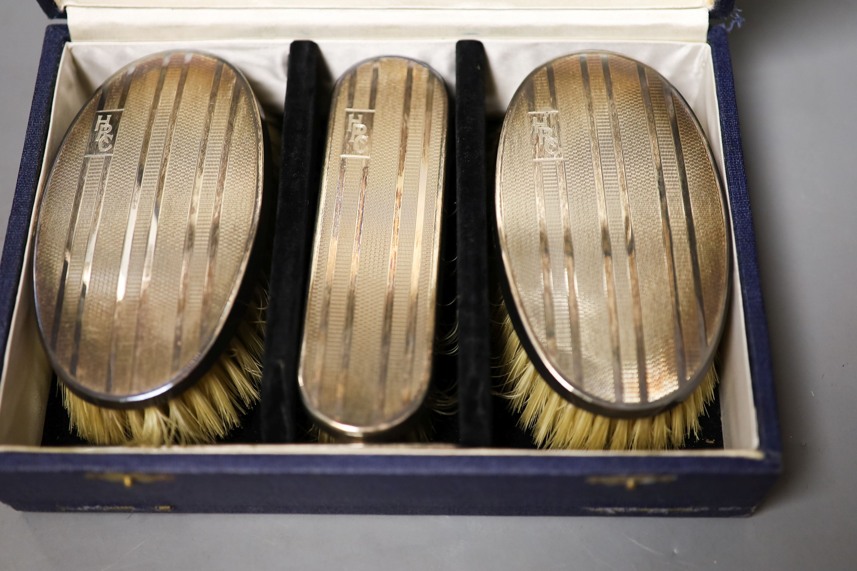 A modern cased silver mounted three piece brush set.